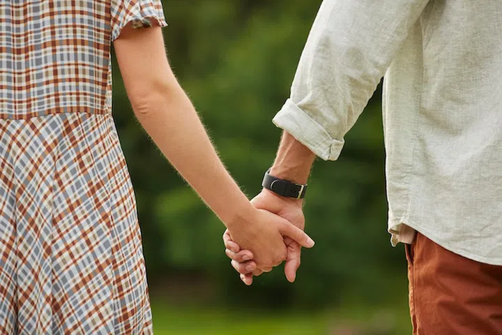 Close up of romantic adult couple holding hands in rustic countryside scenery, copy space