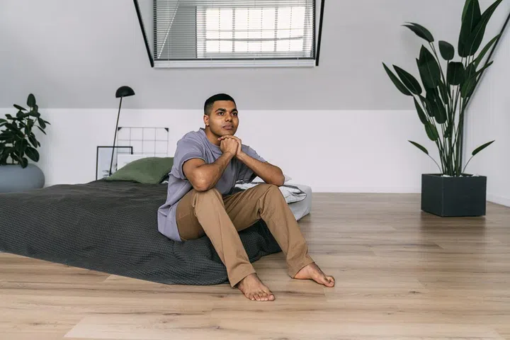 Thoughtful young man sitting on bed at home