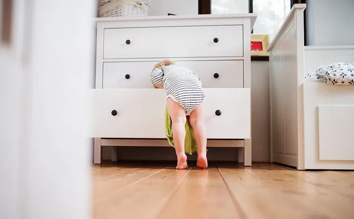 Little toddler boy opening a drawer. Domestic accident. Dangerous situation at home. Rear view.