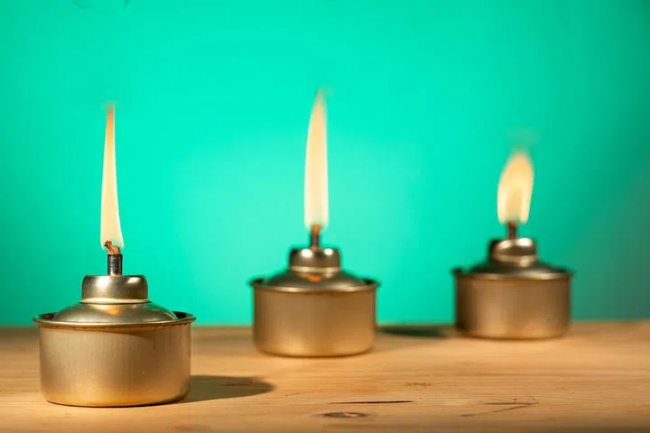 Pelita or oil lamp, traditional Malay oil lamp lit up during Ramadan and Hari Raya Aidilfitri Muslim celebration on green background