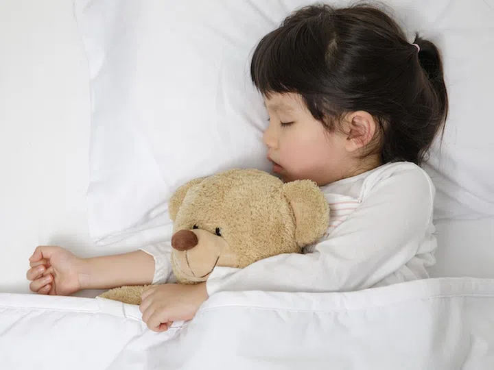 Child girl sleeping with teddy bear on the wooden bed in her bedroom, Happy asian child little girl with her teddy bear, family concept at home