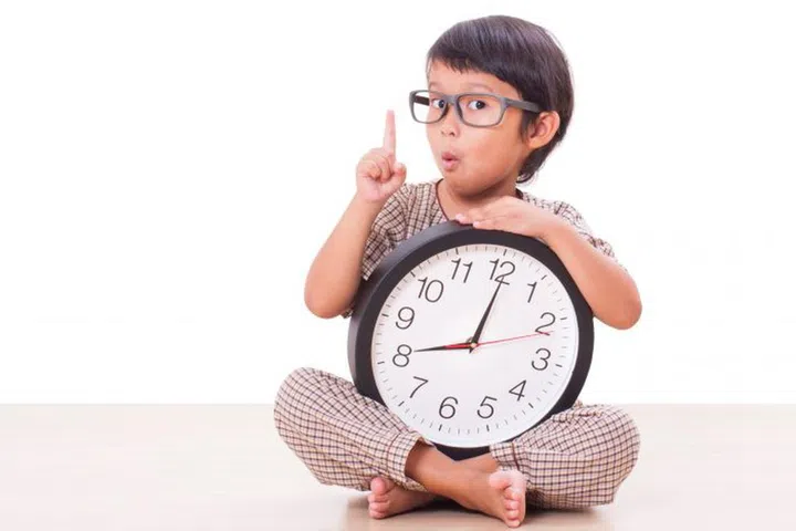 Cute boy is holding big clock isolated on white background