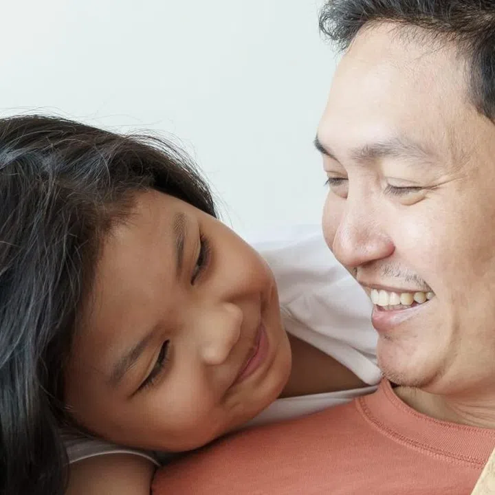 asian father giving gift box for daughter  in the living room. Cute girl and father sitting on sofa be happy  in home