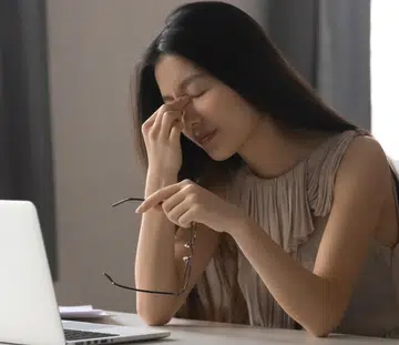 Overworked stressed asian business woman holding glasses feeling eye strain