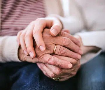 women holding hands with her very elderly mother