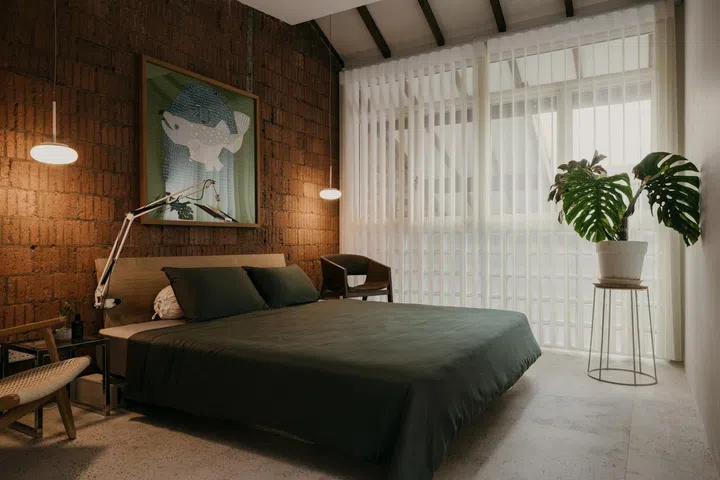The exposed brick of the party wall and glass breezeblocks give the master bedroom a 70s vibe. (Photo: Studio Periphery)