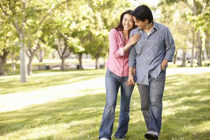 Asian couple walking hand in hand in park