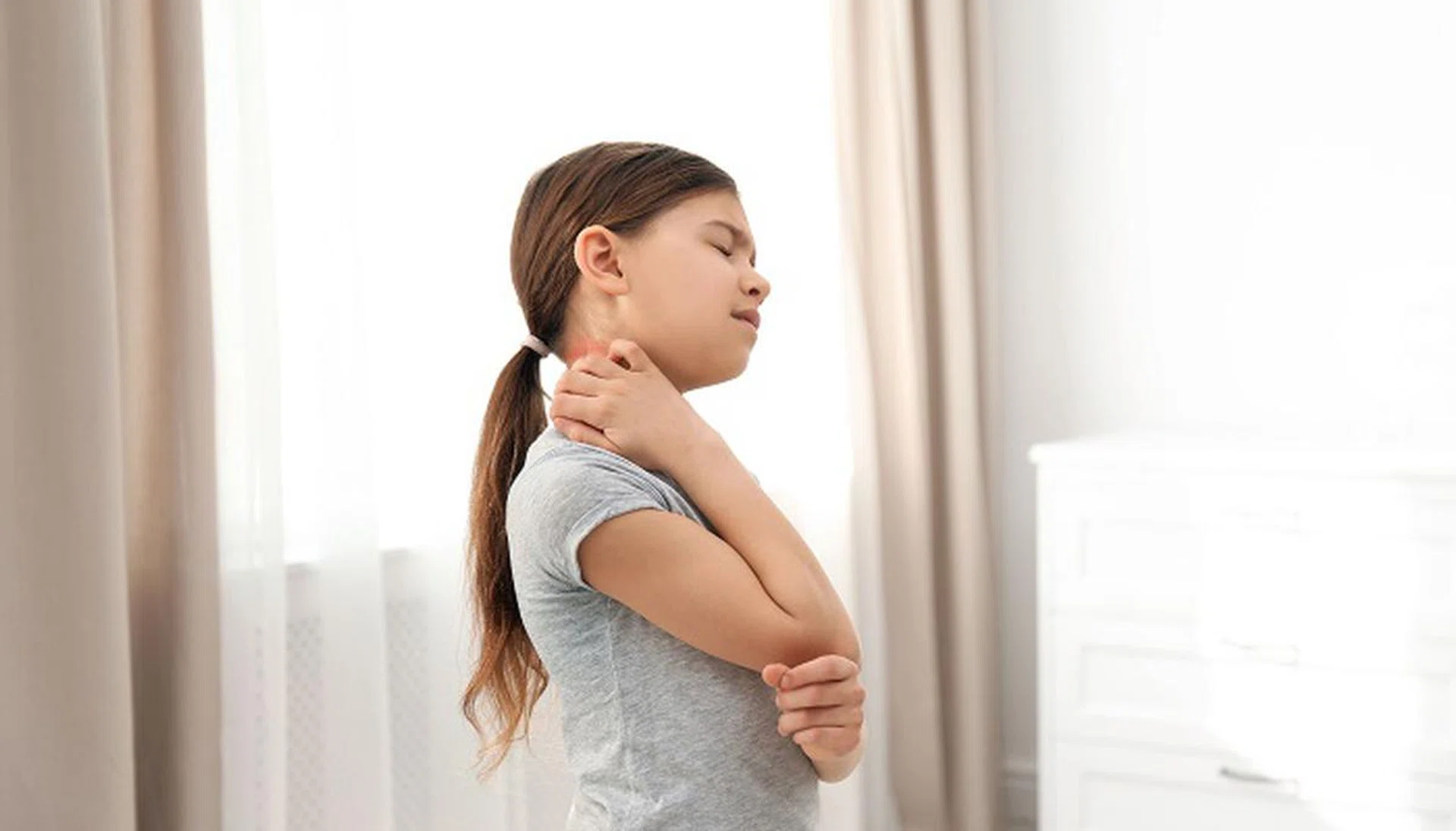 Little girl scratching neck indoors. Allergy symptoms
