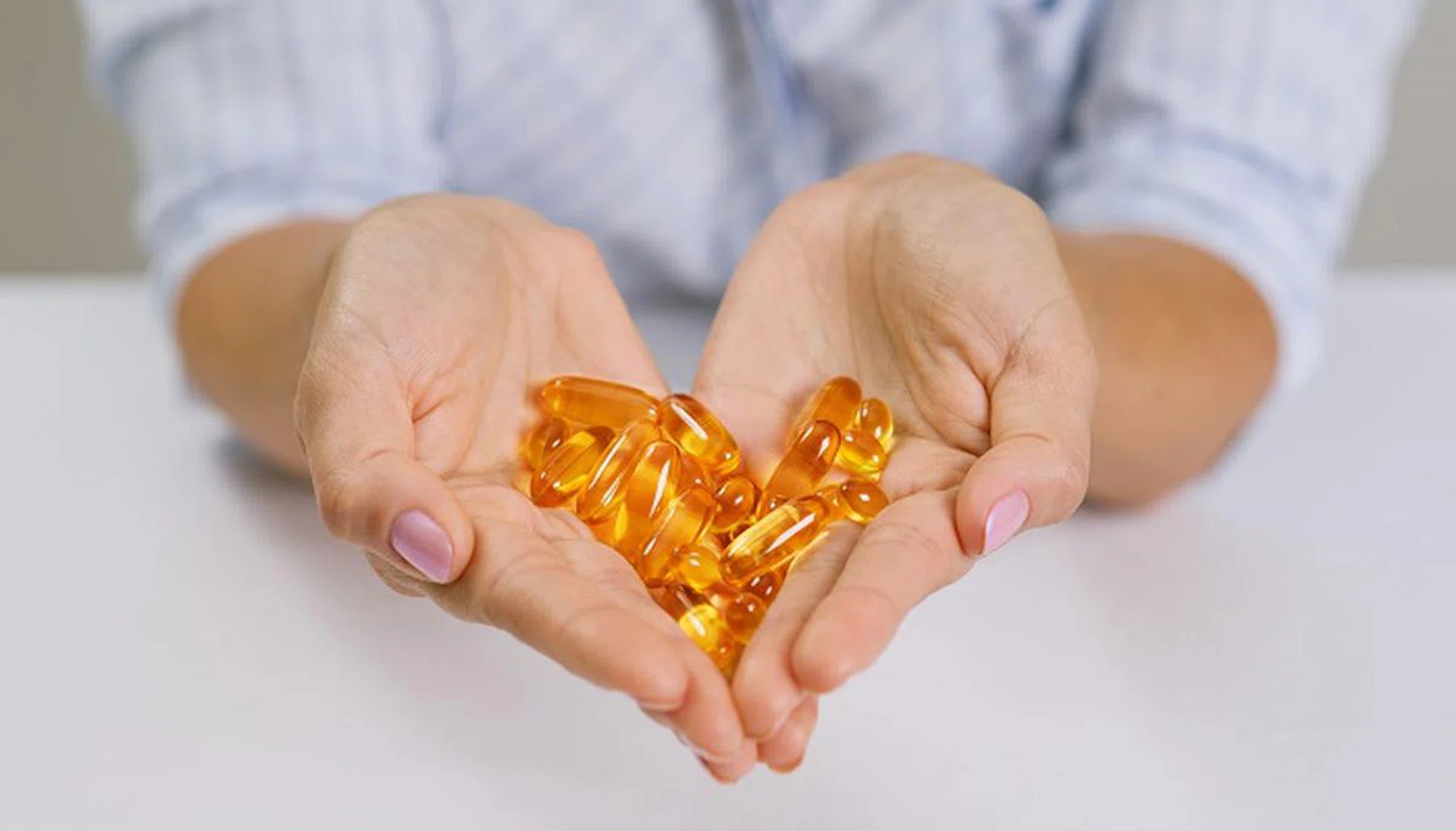 Hands of a woman holding fish oil Omega-3 capsules. Healthy eating, medicine, health care, food supplements and people concept