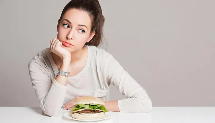 Portrait of a young brunette beauty offering nutrition choices.
