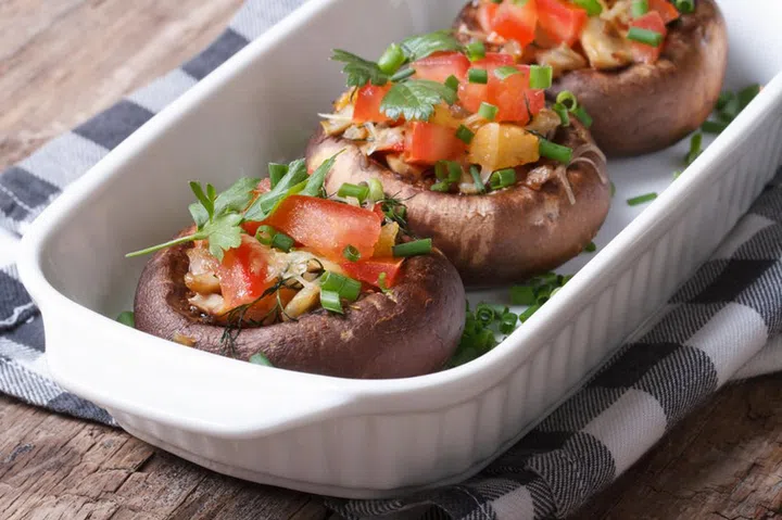 Portobello mushrooms stuffed with vegetables close-up on the table. horizontal