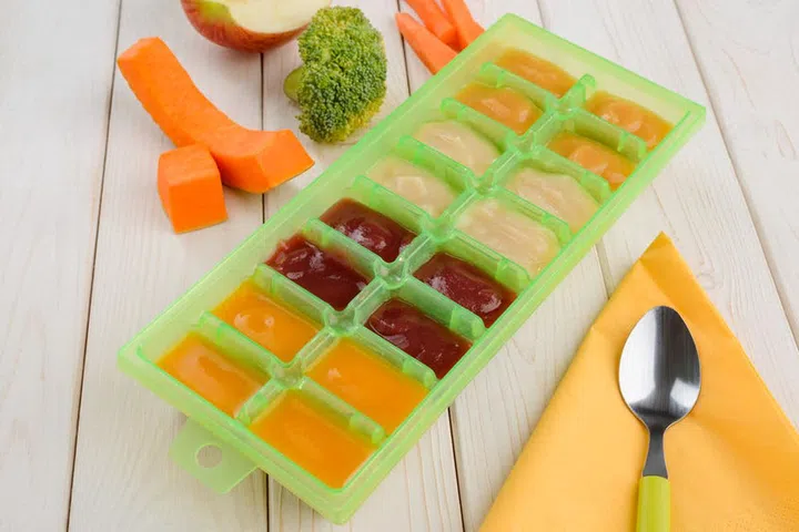 Organic homemade baby food. Precooked assorted veggie puree in multiportion container for storage in freezer.