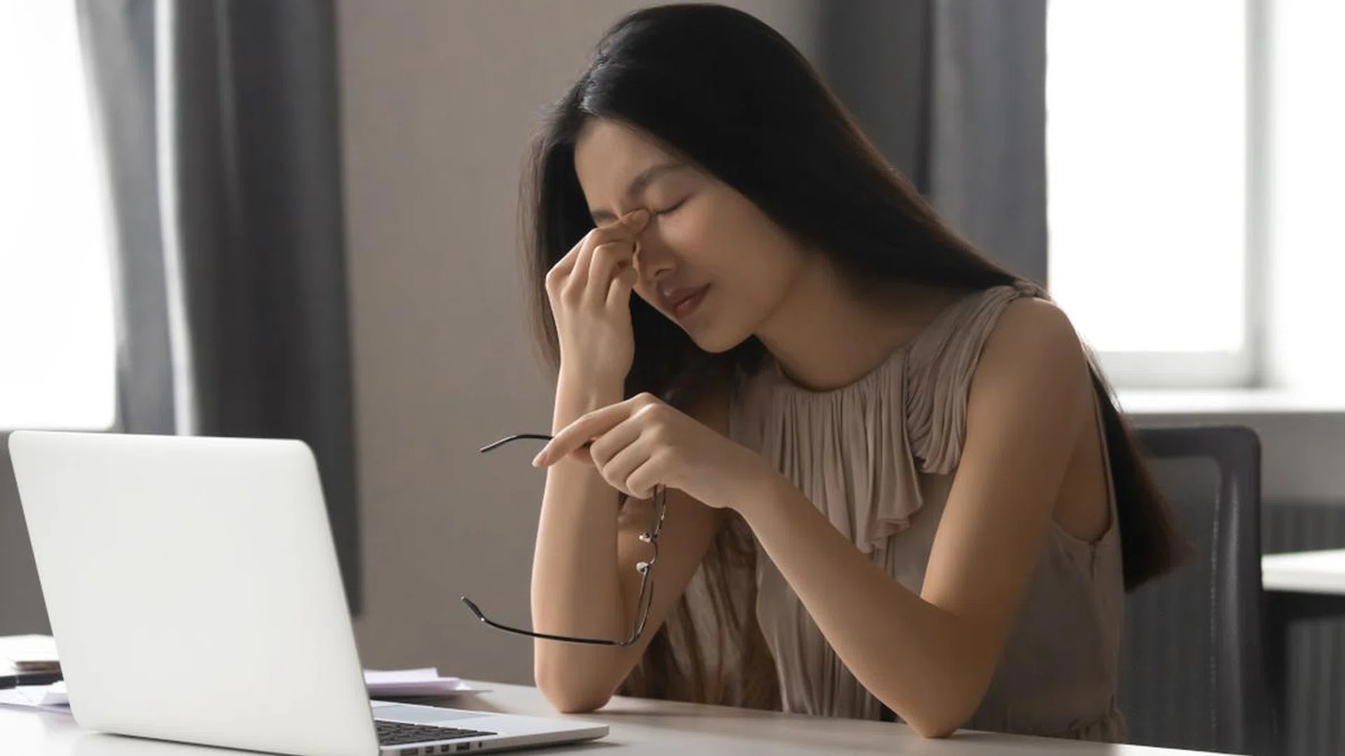 Overworked stressed asian business woman holding glasses feeling eye strain