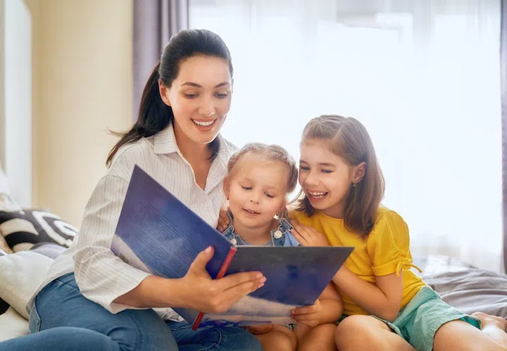 happy loving family. pretty young mother reading a book to her daughters