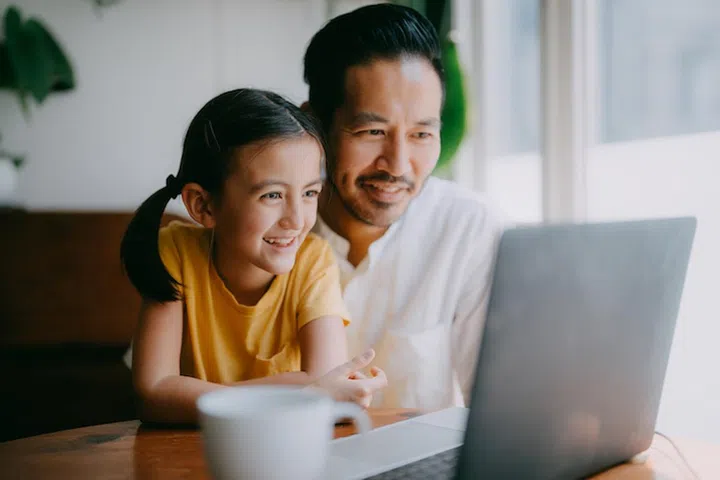 Happy father and young daughter on laptop video call at home, Tokyo