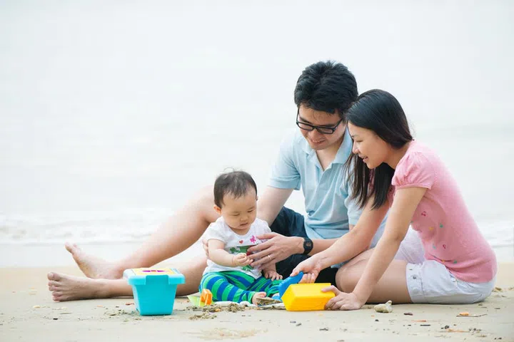 asian family enjoying quality time on the beach with father, mother and daughter

