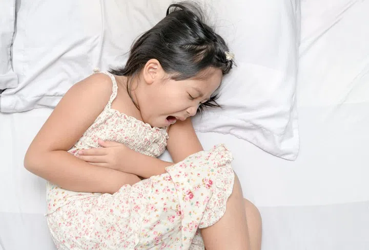asian child suffering from stomachache and lying on bed. diarrhea or healthy concept