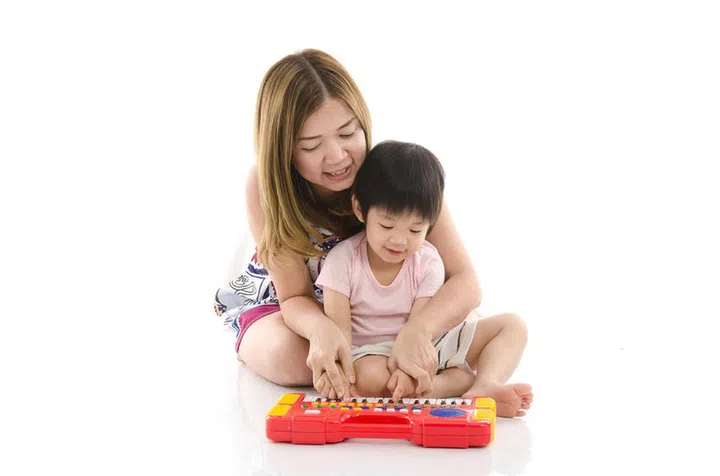 39435027 - cute mother teach her son kid to play electrical toy piano on white background isolated