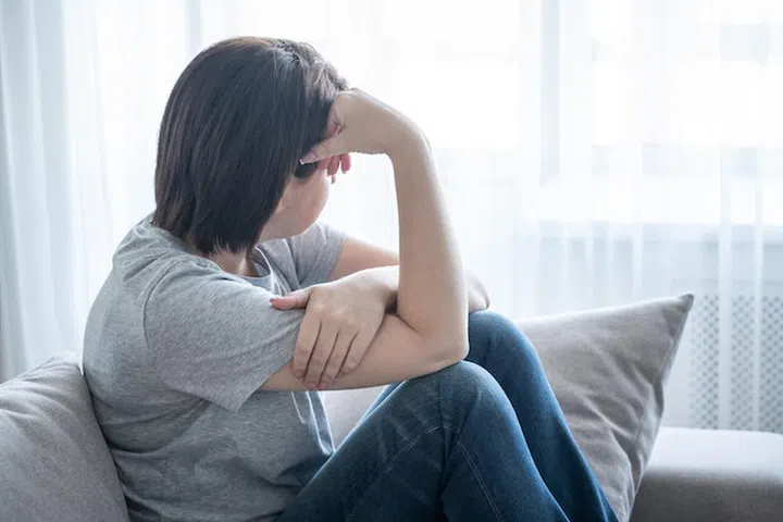sadness girl sits on the sofa at home