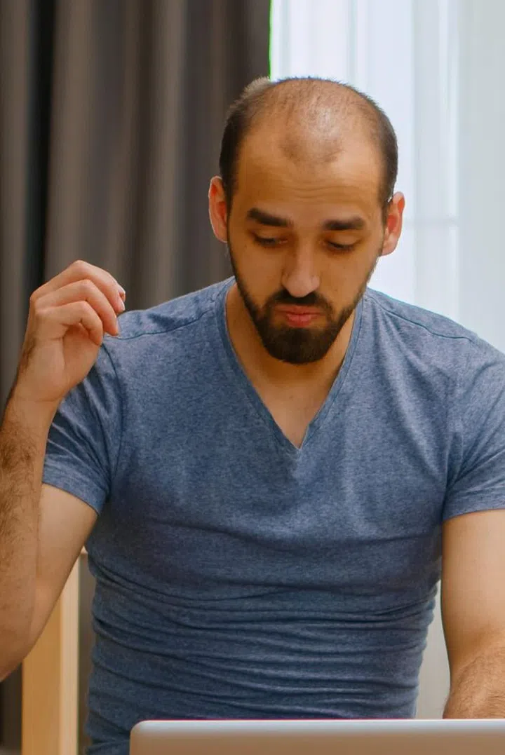 Zoom in shot of angry man on a video call during coronavirus lockdown drinking beer.