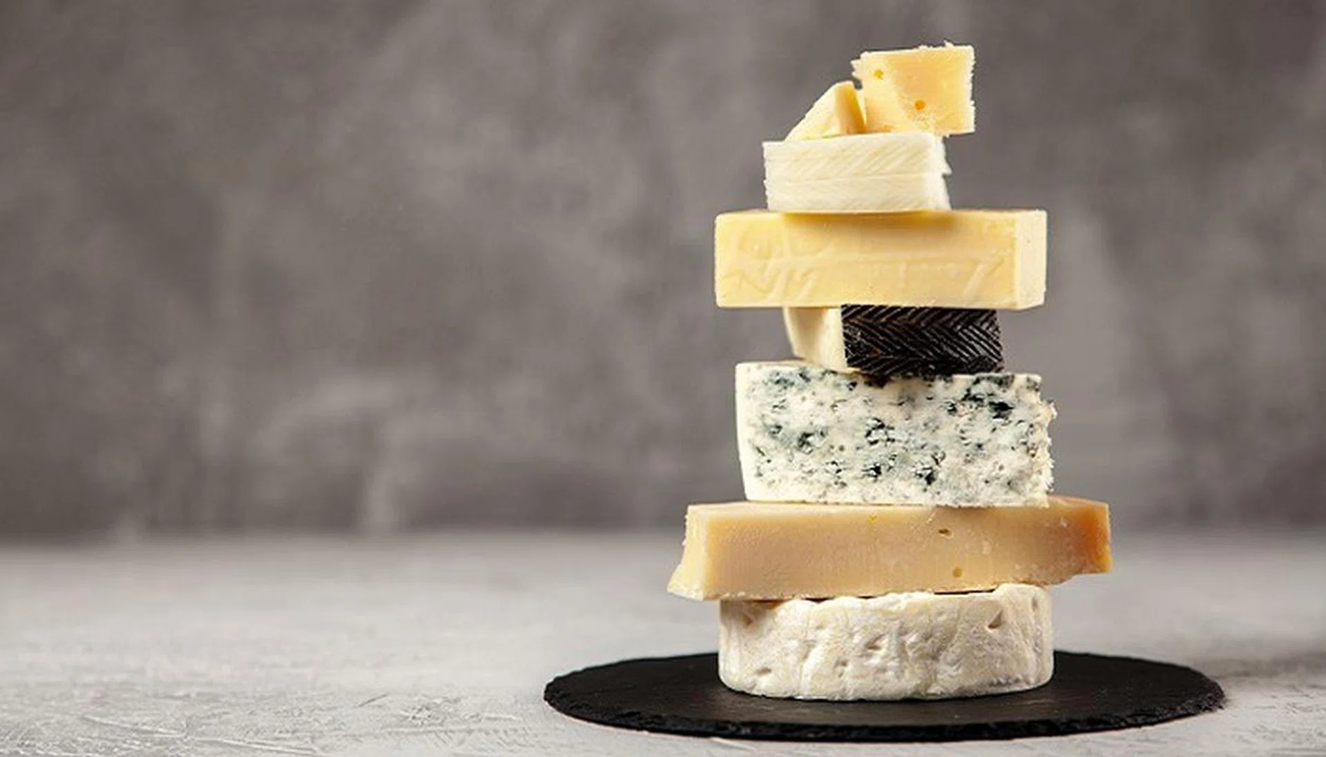 Different sorts of cheese on dark slate background