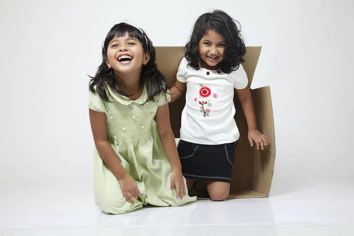 Two little girls coming out from the box