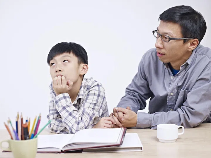 asian father and 10 year-old son having a serious conversation.