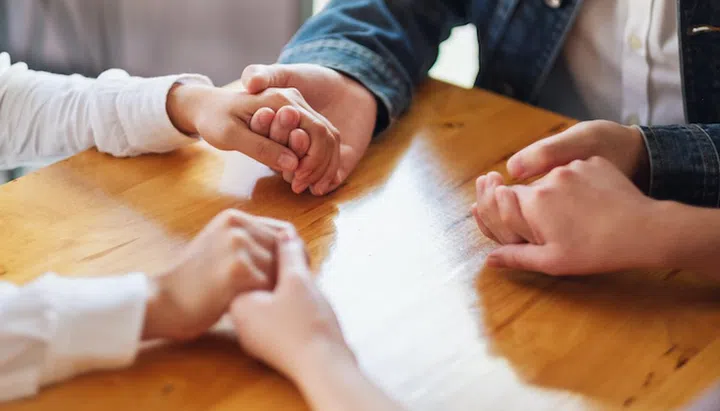 Group of people sitting in a circle holding hands and pray together or in therapy session