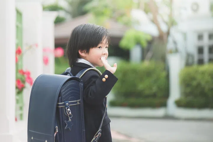 Asian student going to school and waving goodbye