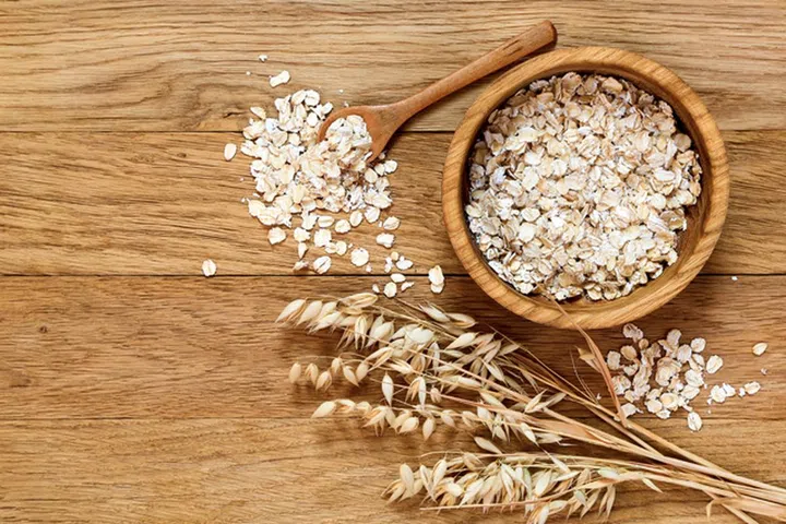 Rolled oats and oat ears of grain on a wooden table, copy space