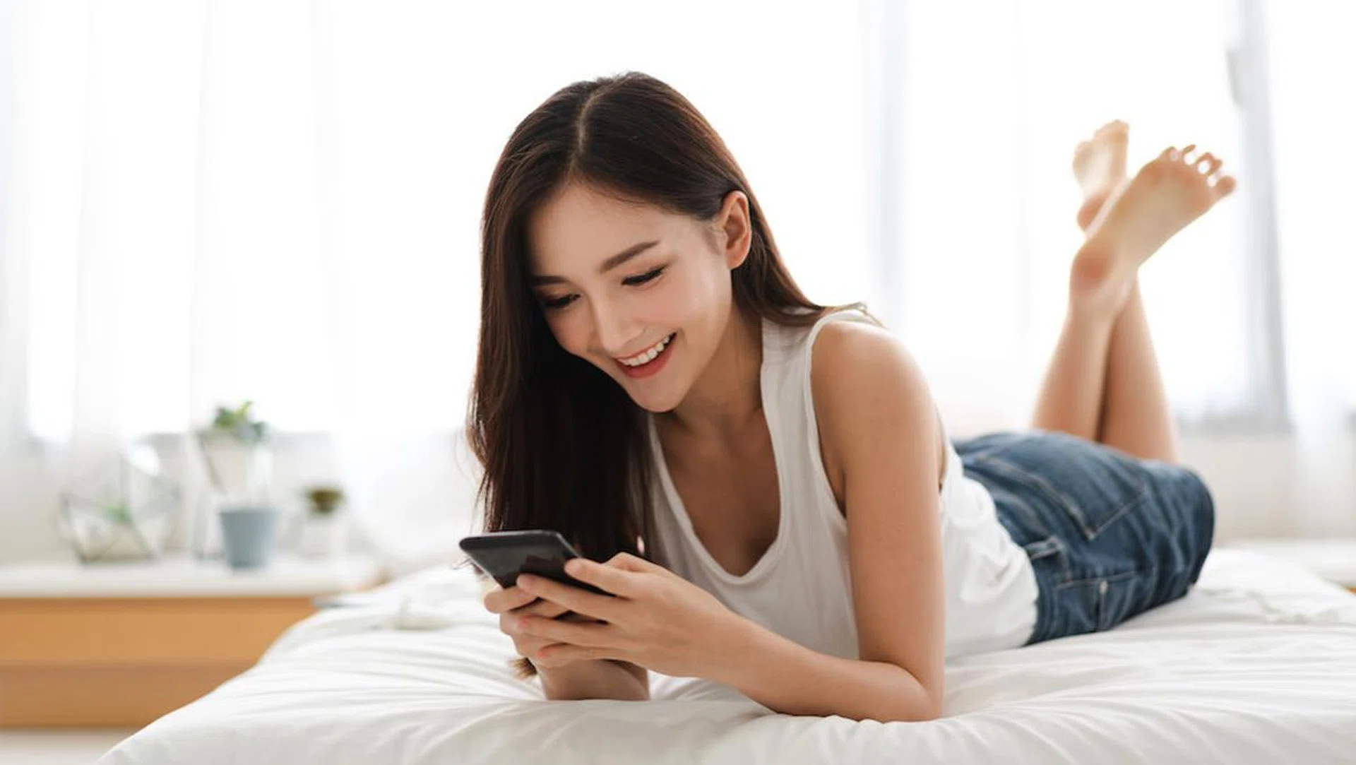 Happy woman relaxing using and talking by smartphone on the bed at home.technology and communication concept