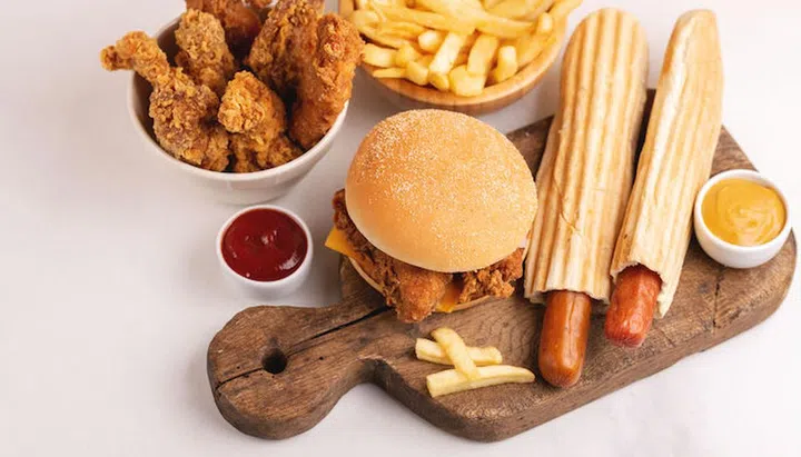 Delicious but unhealthy food with ketchup and mustard on vintage cutting board. Fast carbohydrates, junk and fast food. Light marble background.