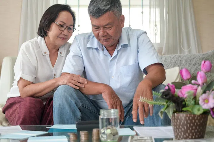 Elderly people check savings with stressful posture.