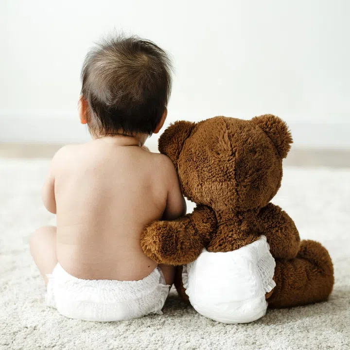Back of a baby with a teddy bear