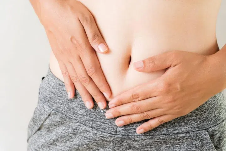 Young woman having painful stomachache. Chronic gastritis. Abdomen bloating concept.