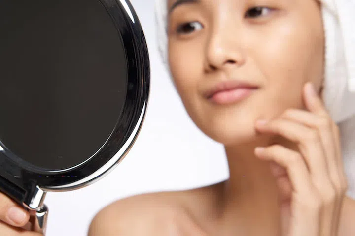 pretty woman looking in the mirror healthy skin rejuvenation spa treatments