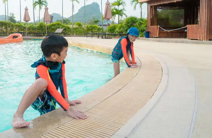 Two Asian siblings in playing together in Water Aqua park pool.