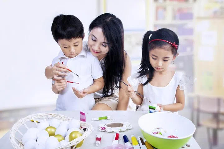 17642972 - happy family painting easter eggs in art class