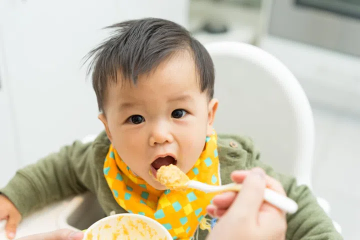 Asian baby boy eating blend food on a high chair