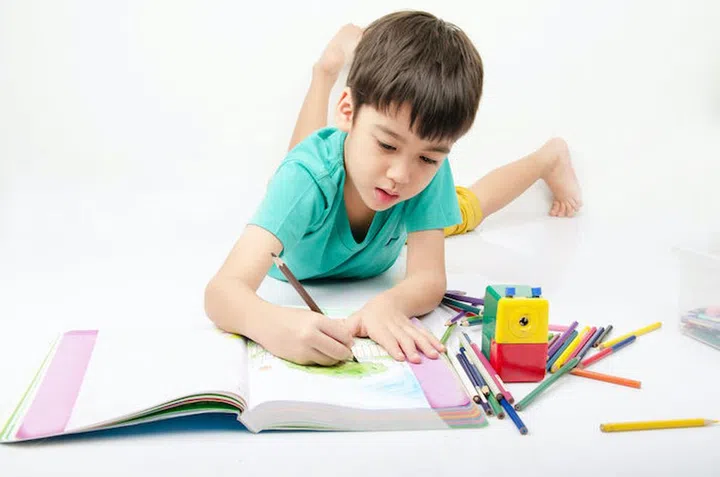 Little boy coloring image lay on th floor