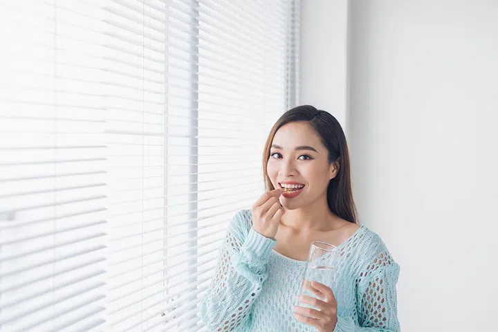 Young asian beauty young woman eating pills and drinking water