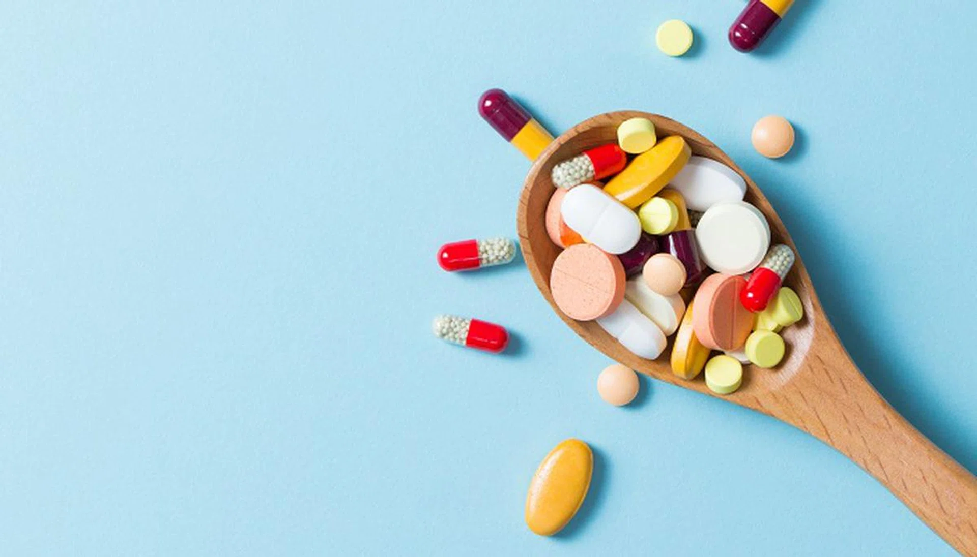 Assorted pharmaceutical medicine pills, tablets and capsules on wooden spoon