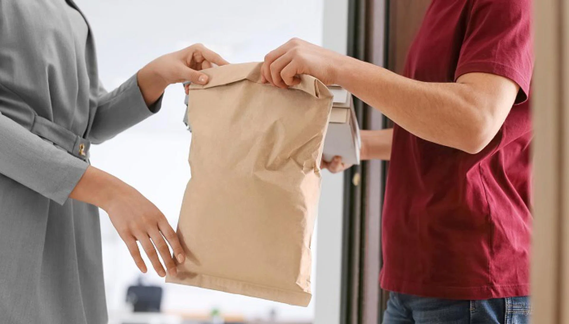 Young woman receiving order from courier. Food delivery service