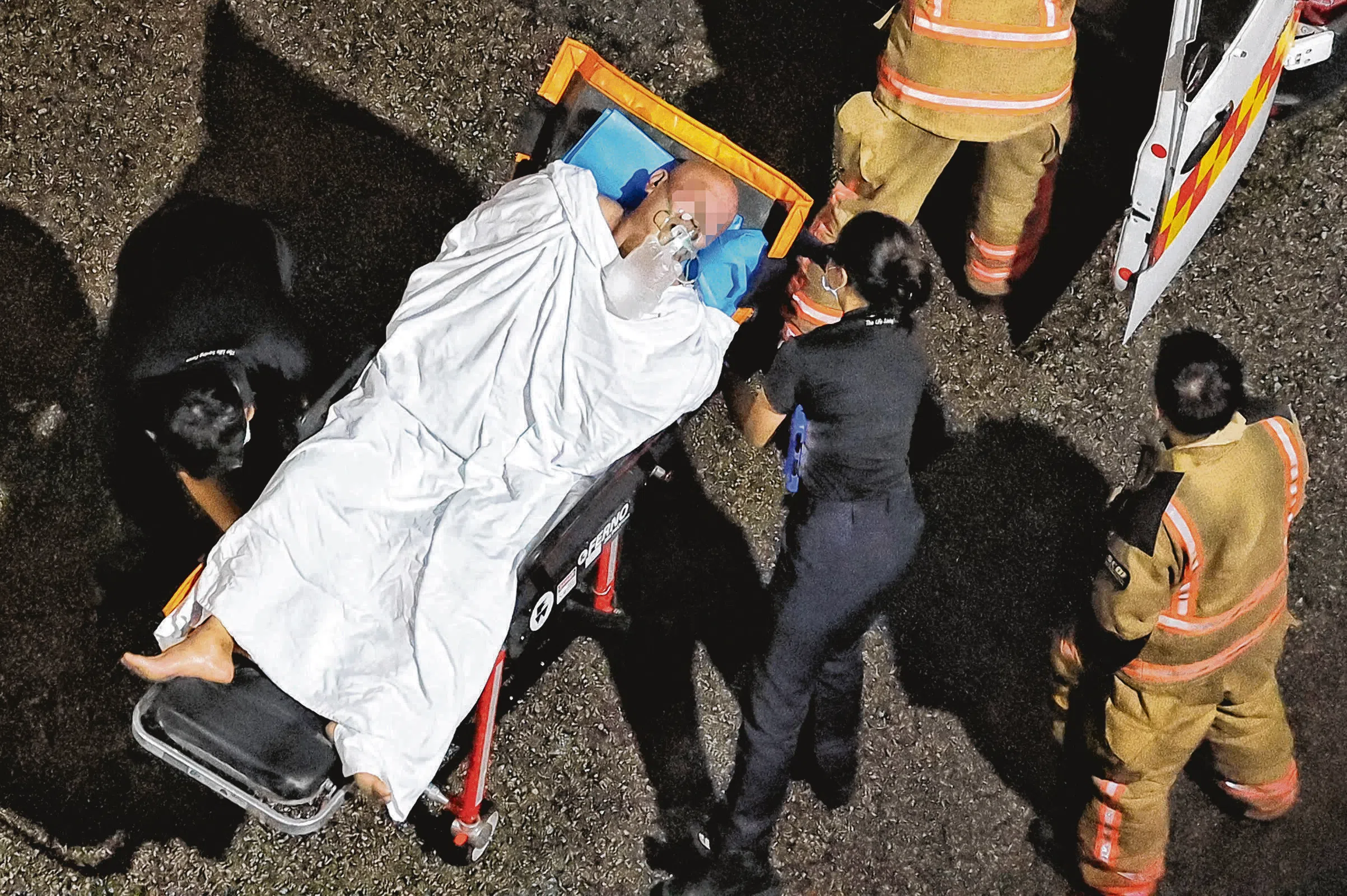 一名阿叔戴着氧气罩，被抬入救护车。（徐颖荃摄）