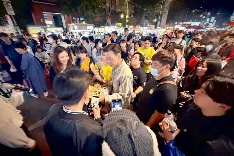 李国煌和李铭顺到夜市宣传，被热情民众包围。（互联网）