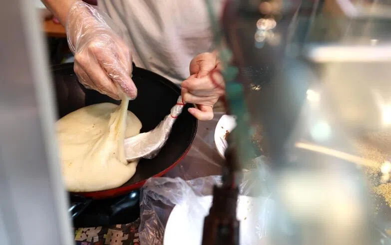 张先生说，他要手工捏出每颗麻糍，顾客才能吃出弹性的口感。（纪允贤摄）
