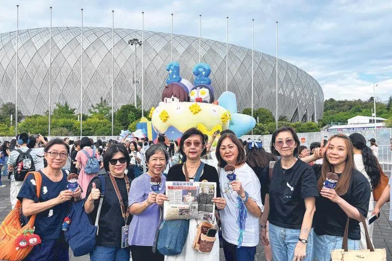 新加坡“生米”组团前往贵阳支持周深，陈佩璇（中）带本报分送海外粉丝。（受访者提供）