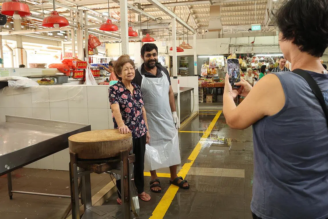 在林秋月鱼摊对面售卖羊肉的摊贩依克巴视她为榜样，对她由衷佩服。（蔡振鸿摄）