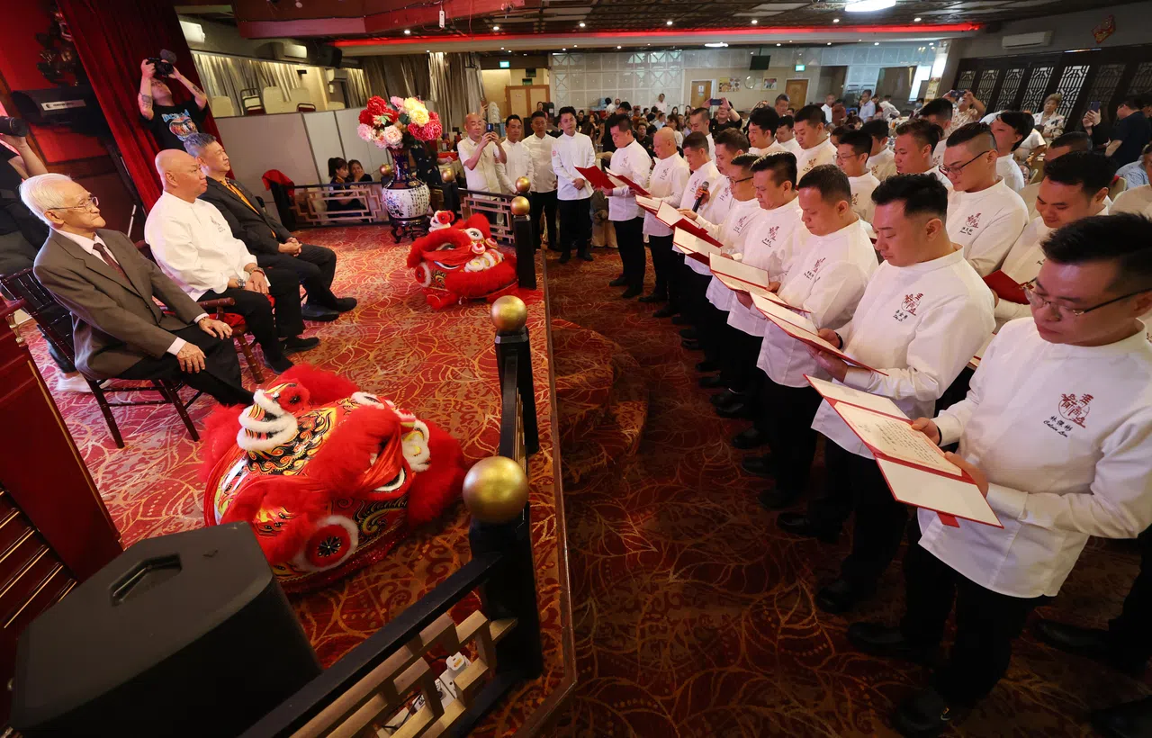 名厨冯洱迅（台上白衣者）的徒弟们一起朗诵师训，代表已入师门。（刘启成摄）