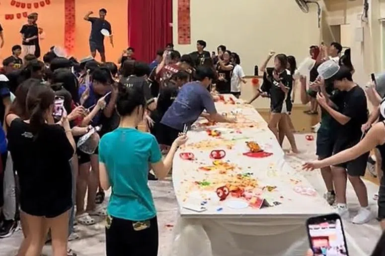 南大学生日前举办捞鱼生活动，有学生从台上往下扔食材。（社媒视频截图）